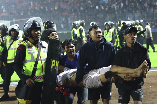 Футбольные болельщики несут раненого после давки во время матча на стадионе Канжурухан в Маланге, Восточная Ява, Индонезия. - Sputnik Таджикистан