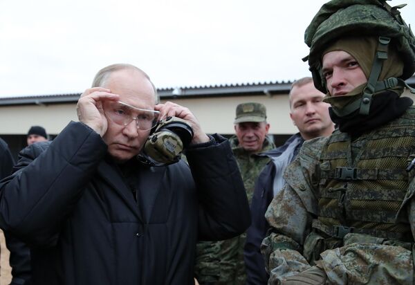 Путин, надев защитные очки и наушники, сам сделал несколько тестовых выстрелов по мишени. - Sputnik Таджикистан