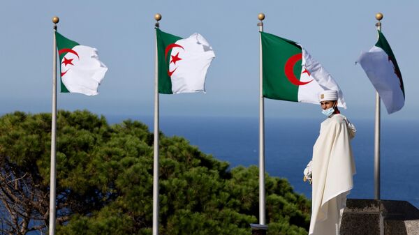 Мужчина проходит мимо флагов в Алжире - Sputnik Таджикистан
