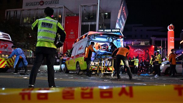 Сеульские спасатели помогают пострадавшим и вывозят погибших с улицы, где во время празднования Хэллоуина из-за давки остановилось сердце у десятков людей, Южная Корея - Sputnik Таджикистан