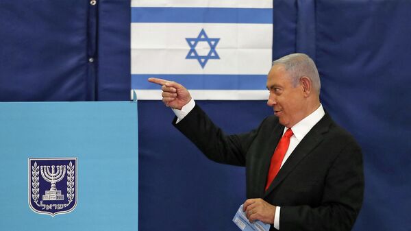 Премьер-министр Израиля Биньямин Нетаньяху жестикулирует во время голосования на избирательном участке в Иерусалиме  - Sputnik Тоҷикистон