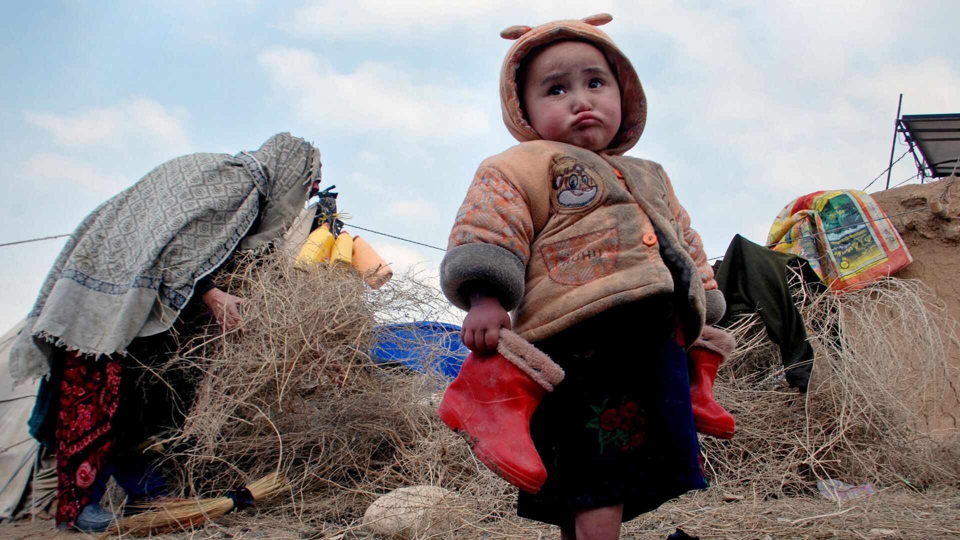 Афганский ребенок с сапожками в руках в лагере для внутренне перемещенных лиц на окраине Мазари-Шарифа, к северу от Кабула, Афганистан, 2014 год - Sputnik Тоҷикистон, 1920, 02.12.2022