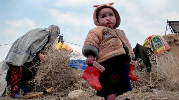 Афганский ребенок с сапожками в руках в лагере для внутренне перемещенных лиц на окраине Мазари-Шарифа, к северу от Кабула, Афганистан, 2014 год - Sputnik Тоҷикистон