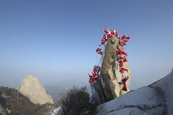 Скалолазы в костюмах Санта-Клауса карабкаются по горе Бухан в Южной Корее. - Sputnik Таджикистан