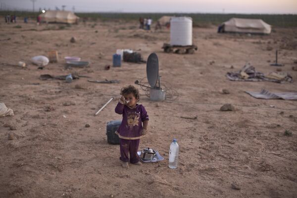 Сирийская беженка пьет чай, стоя возле палатки своей семьи в палаточном поселении недалеко от сирийской границы на окраине Мафрака, Иордания. - Sputnik Таджикистан