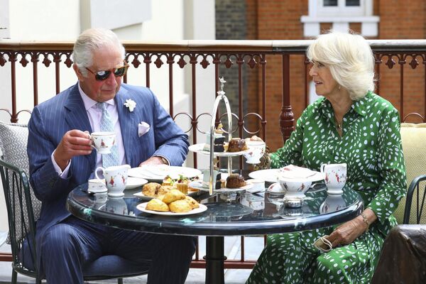 Британский принц Чарльз и Камилла, герцогиня Корнуолльская пьют послеобеденный чай на террасе во время посещения Королевского театра в центре Лондона. - Sputnik Таджикистан