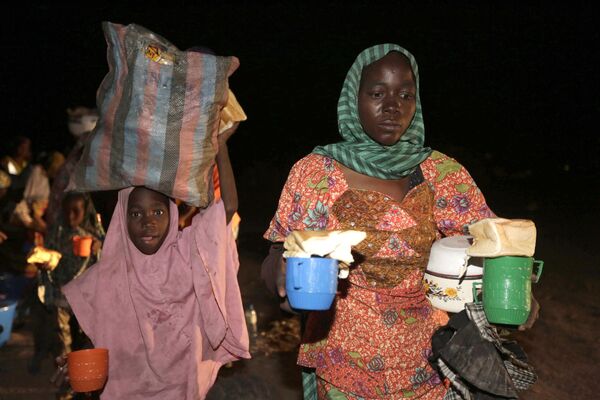 Женщина и ребенок, спасенные нигерийскими солдатами от экстремистов Боко Харам несут чай и хлеб в лагере беженцев в Нигерии. - Sputnik Таджикистан