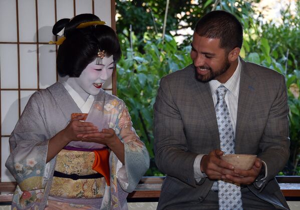 Американский профессиональный бейсбольный питчер Гектор Сантьяго (справа) учится пить японский зеленый чай у девушки-гейши (слева) в Токио. - Sputnik Таджикистан