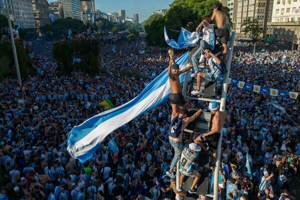 Жители Буэнос-Айреса не сдерживают эмоции и празднуют триумф с национальной символикой, повсюду возвышая национальный флаг. - Sputnik Таджикистан