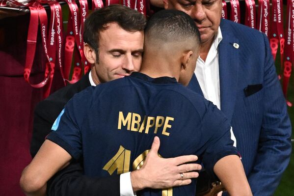 Президент Франции Эммануэль Макрон обнимает нападающего сборной Килиана Мбаппе после поражения в финале ЧМ - 2022 в Катаре. - Sputnik Таджикистан