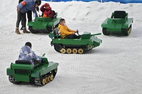 Дети катаются на игрушечных танках по снегу в общественном парке Пекина. - Sputnik Таджикистан