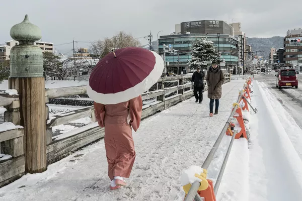 Пешеходы пересекают заснеженный мост через реку Камо в Киото Пешеходы пересекают заснеженный мост через реку Камо в Киото
