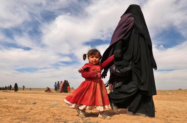 Женщина в полном хиджабе (чадре) вместе с девочкой во время эвакуации из Сирии. - Sputnik Таджикистан