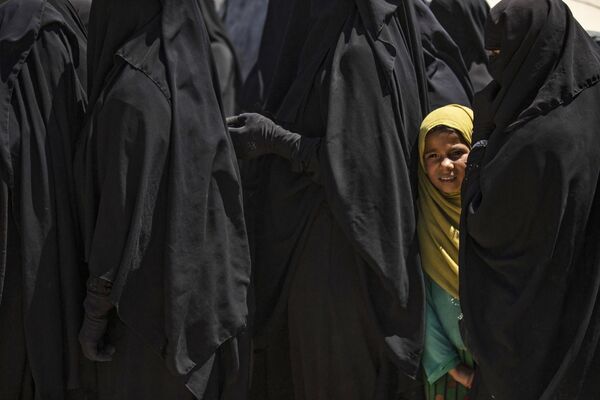 Девочка в ярком хиджабе стоит в очереди за помощью вместе с женщинами в курдском лагере Аль-Холь в Сирии. - Sputnik Таджикистан