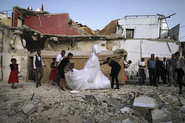 Бывает и такое: палестинская невеста и жених начинают свадебную церемонию на руинах дома в восточном иерусалимском районе Сильван. - Sputnik Таджикистан
