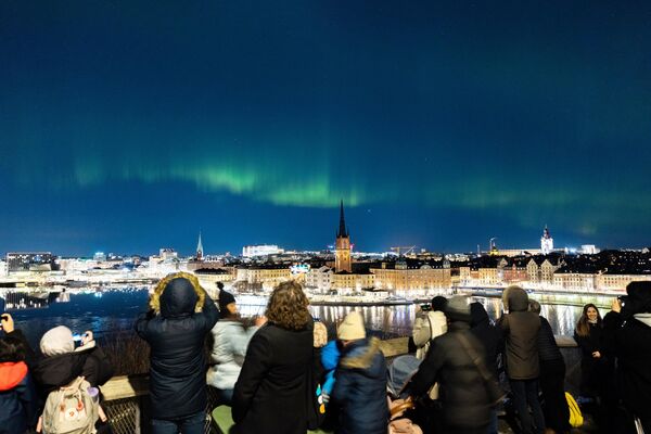 Люди наблюдают за северным сиянием в центре Стокгольма. - Sputnik Таджикистан