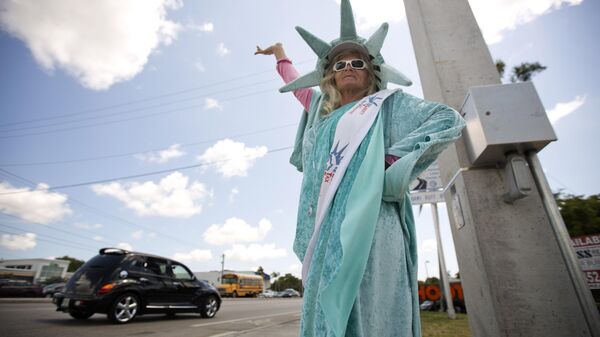Дениз Монсен, одетая как Статуя Свободы, стоит на углу улицы Пембрук-Пайнс, штат Флорида, в последний день крайнего срока подачи документов по подоходному налогу в США - Sputnik Таджикистан
