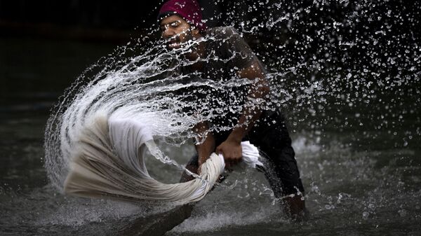 Мужчина стирает одежду на берегу реки Брахмапутра во Всемирный день водных ресурсов в Гувахати, Индия - Sputnik Тоҷикистон