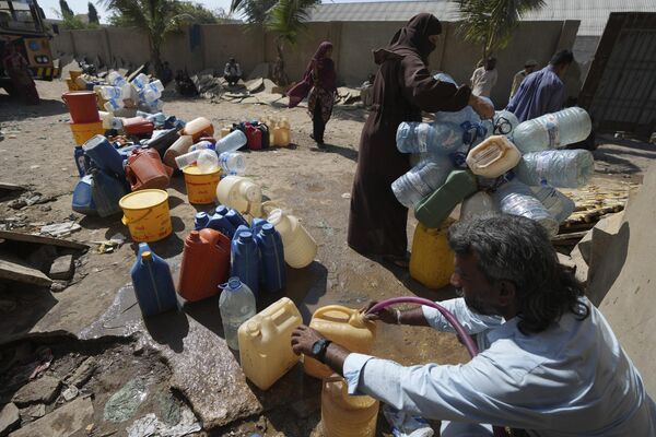Люди берут питьевую воду из пункта сбора воды в районе трущоб в Карачи, Пакистан. - Sputnik Таджикистан