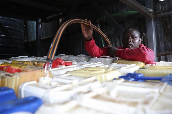 Продавец воды наполняет емкости водой из цистерны в трущобах Кибера в Найроби, Кения. - Sputnik Таджикистан