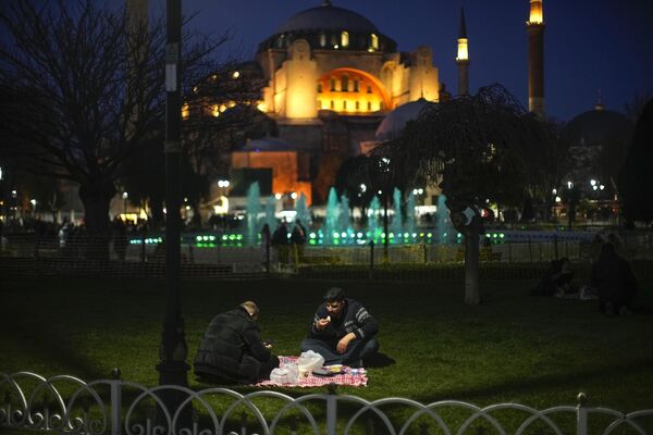 Люди разговляются после заката в первый день Рамадана на фоне мечети византийской эпохи Святой Софии в Стамбуле. - Sputnik Таджикистан