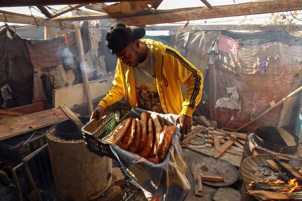 Мужчина несет свежеиспеченный хлеб из тандыра для мусульман в восточном ливийском городе Бенгази. - Sputnik Таджикистан
