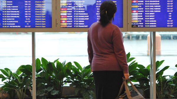 Женщина стоит у табло с расписанием вылетов в аэропорту  - Sputnik Таджикистан