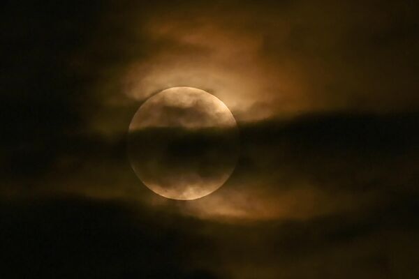 Луна видна сквозь облака во время частичного лунного затмения на севере Индии. - Sputnik Таджикистан