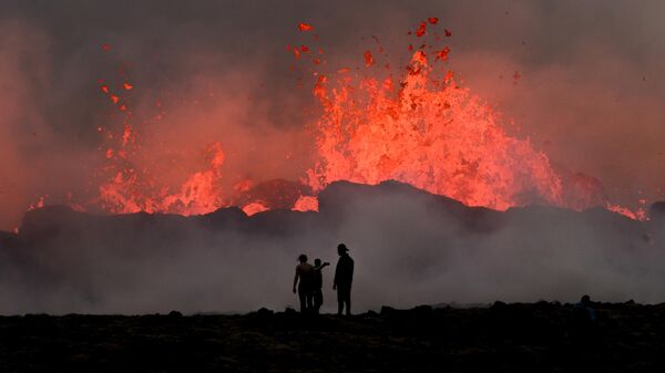 Люди наблюдают за текущей лавой во время извержения вулкана близ Литтл-Хрутура, к юго-западу от Рейкьявика в Исландии - Sputnik Таджикистан