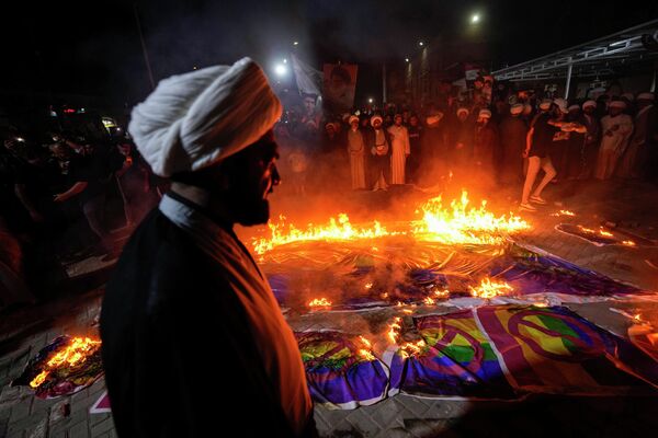 Сторонники лидера мусульман-шиитов Муктады Садра в Багдаде сжигают радужные флаги во время демонстрации в Садр-Сити в ответ на сожжение Корана в Швеции. - Sputnik Таджикистан