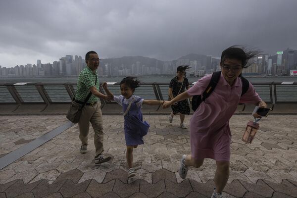 Туристы из материкового Китая бегут по набережной во время тайфуна в Гонконге. - Sputnik Таджикистан