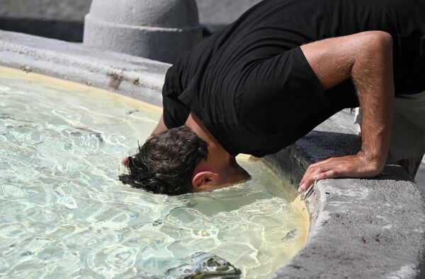 Мужчина опускает голову в воду, чтобы охладиться у фонтана на площади Пьяцца дель Пополо в Риме,. - Sputnik Таджикистан
