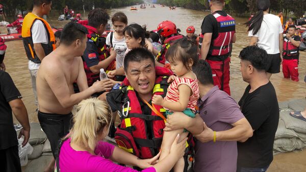 Спасатели на резиновых лодках эвакуируют оказавшихся в ловушке жителей через паводковые воды в Чжуочжоу в провинции Хэбэй на севере Китая - Sputnik Тоҷикистон