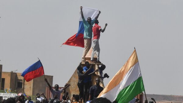 Протестующие размахивают нигерийскими и российскими флагами, собираясь во время митинга в поддержку нигерийской хунты в Ниамее - Sputnik Таджикистан