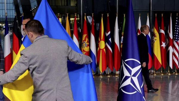 Сотрудник службы протокола поправляет украинский флаг в штаб-квартире НАТО в Брюсселе - Sputnik Таджикистан