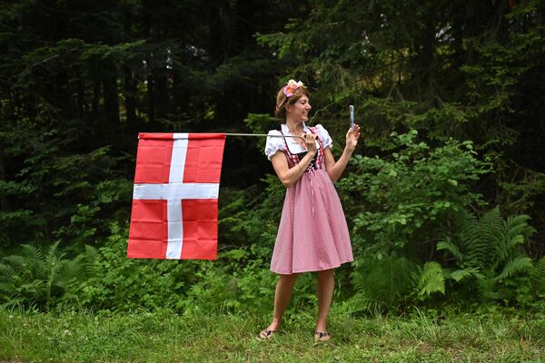 Женщина в традиционной одежде держит датский национальный флаг на маршруте велогонки Тур де Франс. - Sputnik Таджикистан