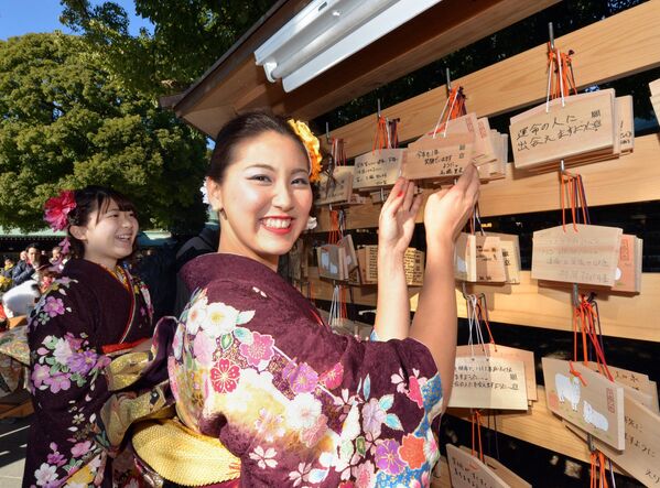 Гиды, одетые в традиционные кимоно, вешают &quot;эма&quot; со своими письменными пожеланиями в храме Мэйдзи в Токио после посещения церемонии очищения. - Sputnik Таджикистан
