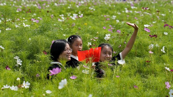 Женщина и две девочки на цветочном поле в Национальный день страны в Ханчжоу, Китай - Sputnik Таджикистан