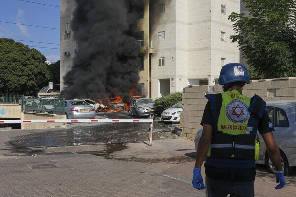 Автомобили горят после того, как ракета, выпущенная из сектора Газа, попала в парковку и жилой дом в Ашкелоне на юге Израиля.. - Sputnik Таджикистан