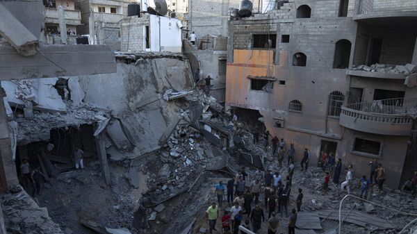 Палестинцы ищут выживших в здании, разрушенном в результате израильской бомбардировки в Хан-Юнисе, сектор Газа - Sputnik Тоҷикистон