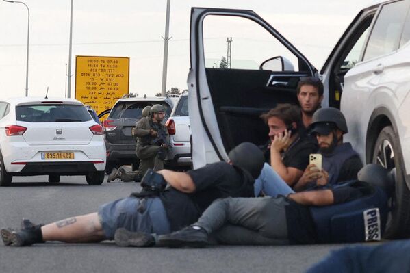 Журналисты прячутся за автомобилями, пока израильские солдаты занимают позиции во время столкновений с палестинскими боевиками возле кибуца Гевим, недалеко от границы с сектором Газа. - Sputnik Таджикистан