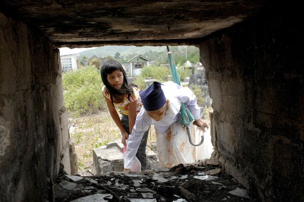 Пожилая женщина и ее внучка (слева) собирают прах из могилы на кладбище острова Сикихор, расположенном в центральной части Филиппин. Сикихор широко известен как мистический остров, где многие травники и целители обладают сверхъестественными способностями. - Sputnik Таджикистан