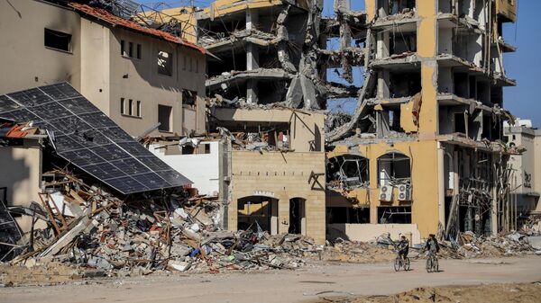 Палестинцы едут на велосипедах мимо разрушенных зданий в городе Газа - Sputnik Тоҷикистон