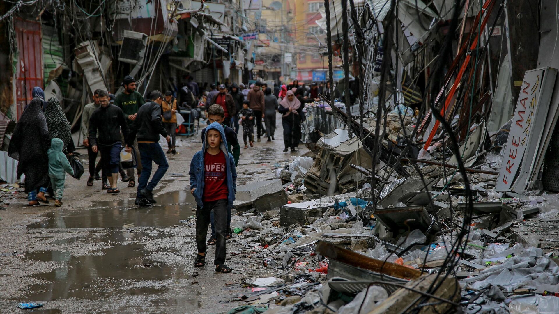 Палестинцы идут среди обломков зданий, пострадавших в результате израильских ударов, возле рынка Аль-Завия в городе Газа - Sputnik Тоҷикистон, 1920, 09.12.2023