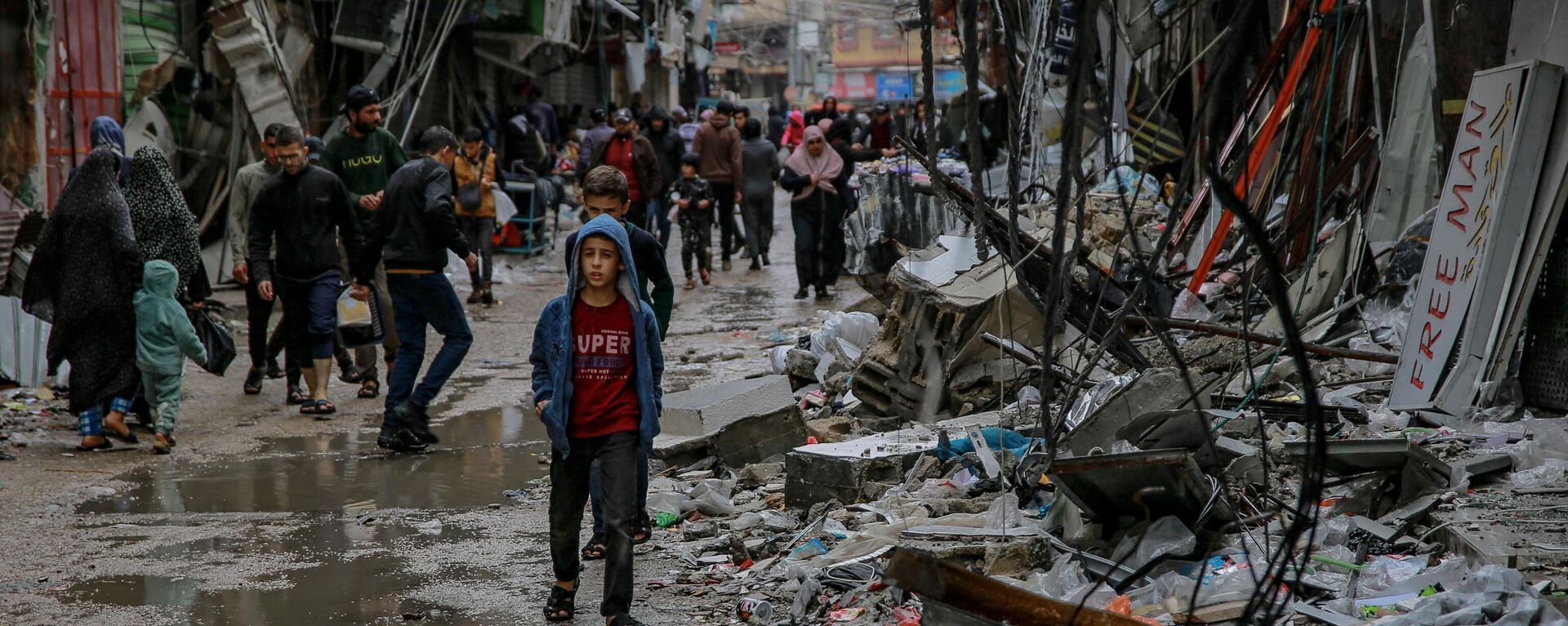 Палестинцы идут среди обломков зданий, пострадавших в результате израильских ударов, возле рынка Аль-Завия в городе Газа - Sputnik Тоҷикистон, 1920, 09.12.2023