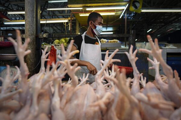 Продавец в маске, чтобы помочь сдержать распространение коронавируса, готовит птиц на рынке в центре Куала-Лумпура, Малайзия. - Sputnik Таджикистан