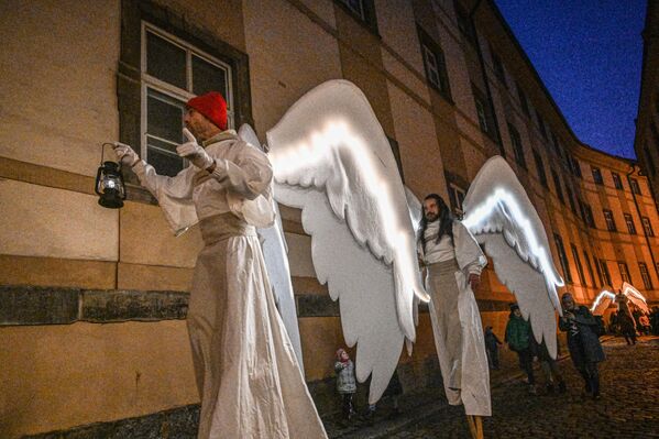Артисты в костюмах ангелов идут на ходулях во время рождественского парада ангелов 17 декабря в Праге. - Sputnik Таджикистан