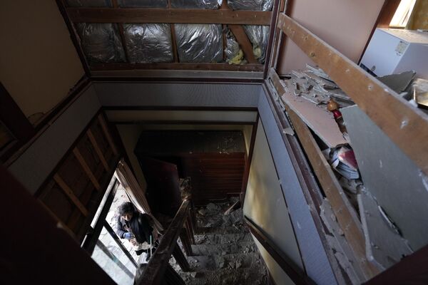 Человек смотрит на поврежденный дом после сильного землетрясения. - Sputnik Таджикистан