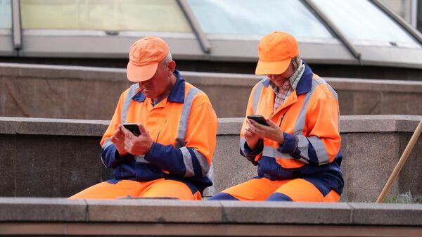 Два дворника сидят со смартфонами на Манежной площади в Москве - Sputnik Тоҷикистон