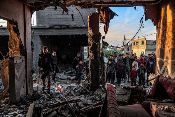 Люди стоят среди обломков здания в Рафахе. - Sputnik Таджикистан